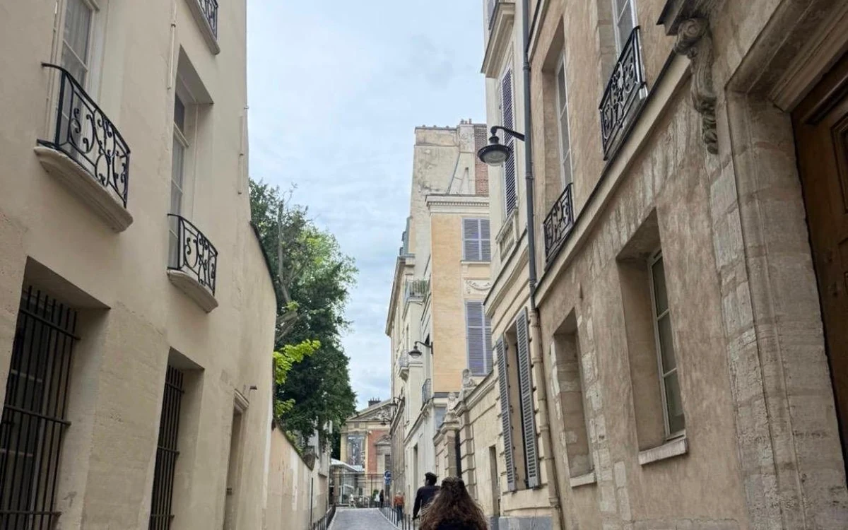 A cyclist heading down a narrow street of old Paris between shuttered stone houses