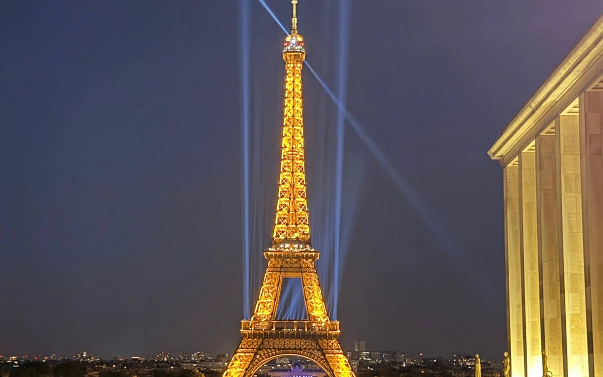 The Arc de Triomphe floodlit at night with traffic circling in front of it