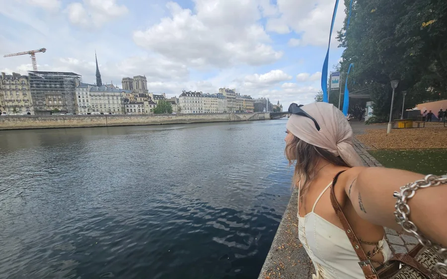 The wake of a boat on the Seine, a bridge and the French flag ahead