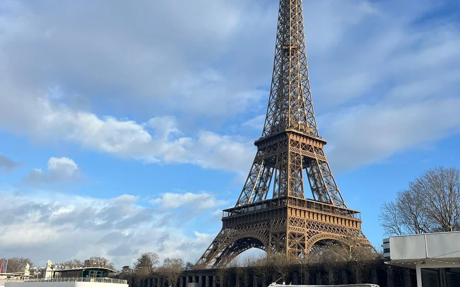 The Eiffel Tower from the river bank with a boat passing
