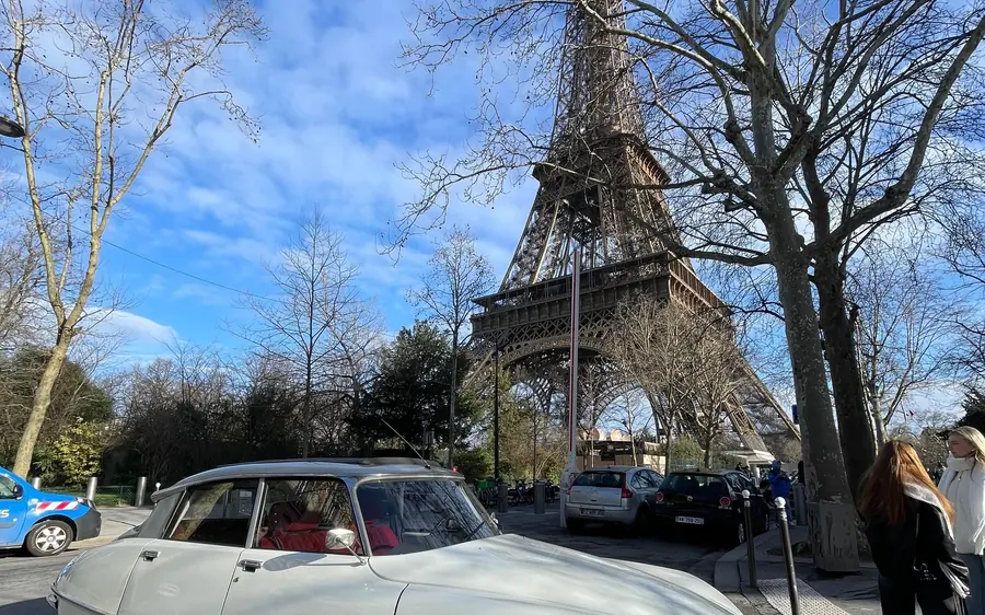 A vintage Citroën DS parked under the trees near the Eiffel Tower