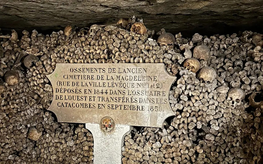 A wall of skulls and bones with a carved plaque in the Catacombs