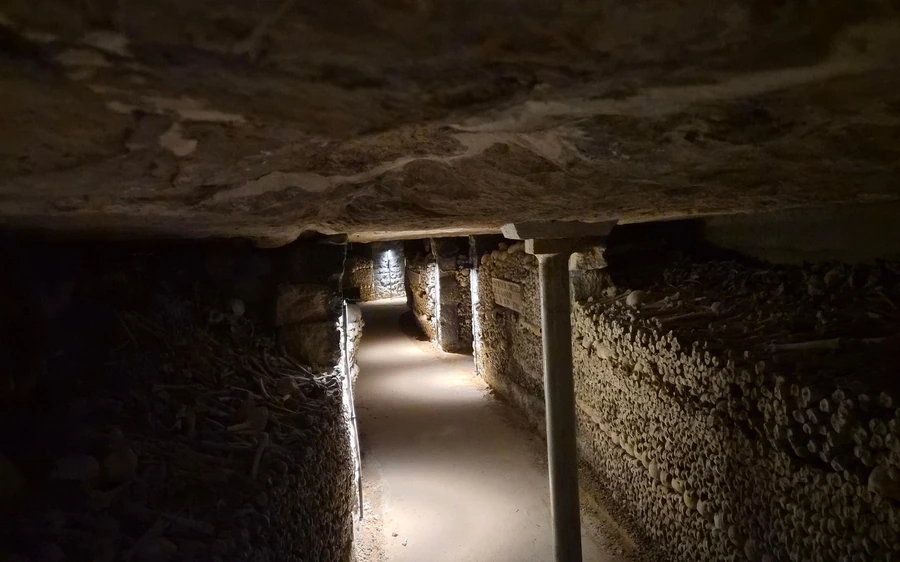 A narrow stone passage in the Catacombs lit by a single lamp