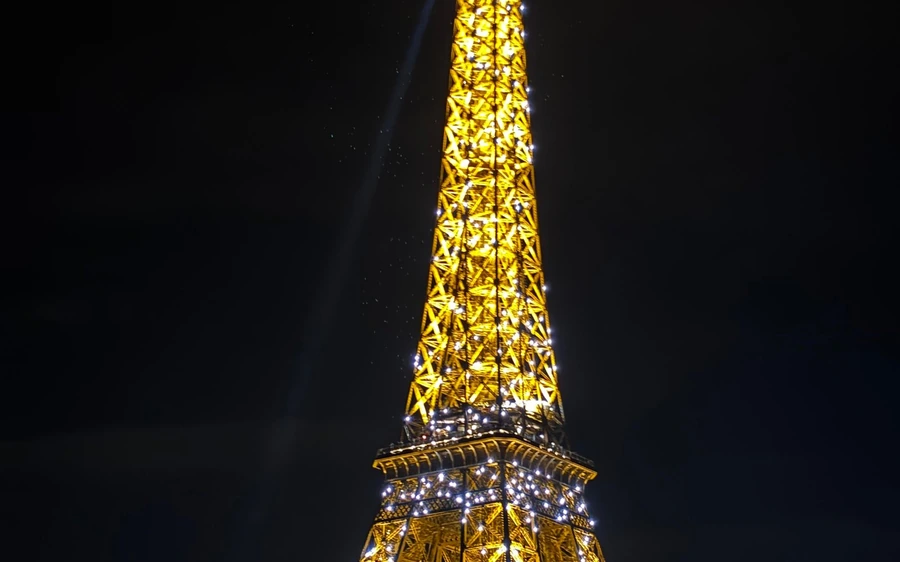 The Eiffel Tower lit gold against the night sky