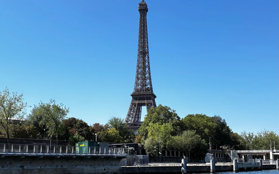 The Eiffel Tower above the trees of the quay, seen from a boat on the Seine