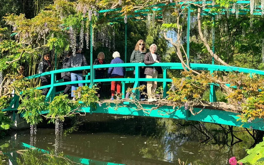 Visitors on the green bridge under wisteria in Monet’s garden at Giverny