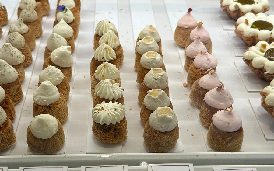 Rows of small cream-topped pastries in a patisserie window
