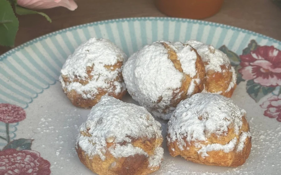 Sugar-dusted choux pastries on a flowered plate
