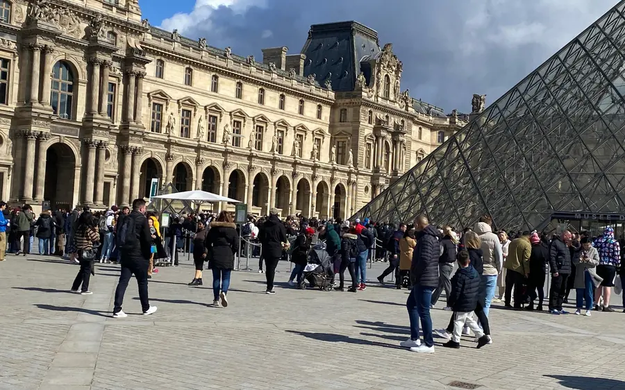 Visitors crossing the Louvre courtyard beside the pyramid