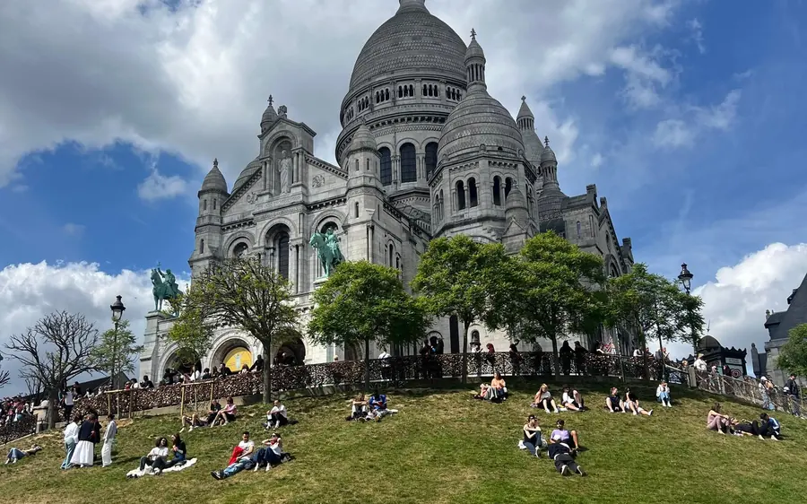 The Sacré-Cœur basilica with people sitting on the lawns below