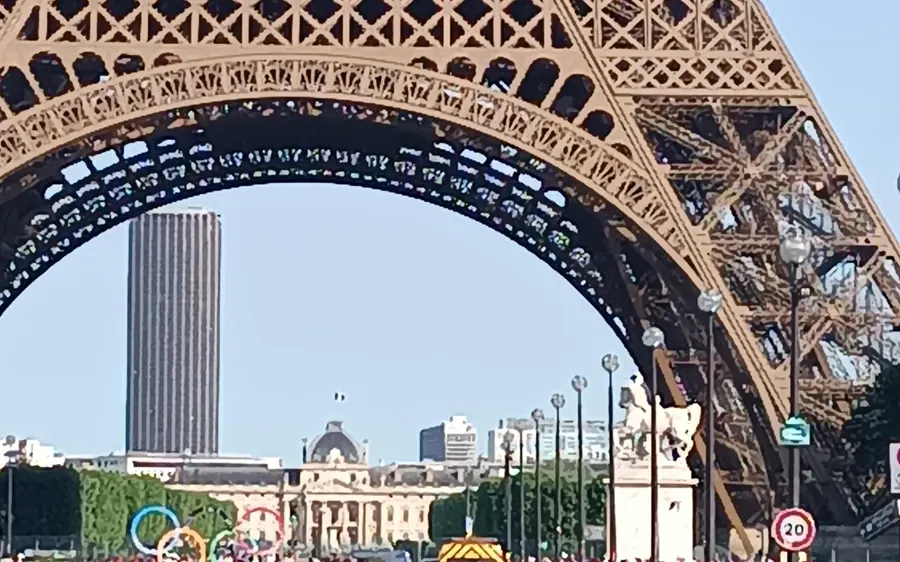 Looking up through the arch of the Eiffel Tower toward the city
