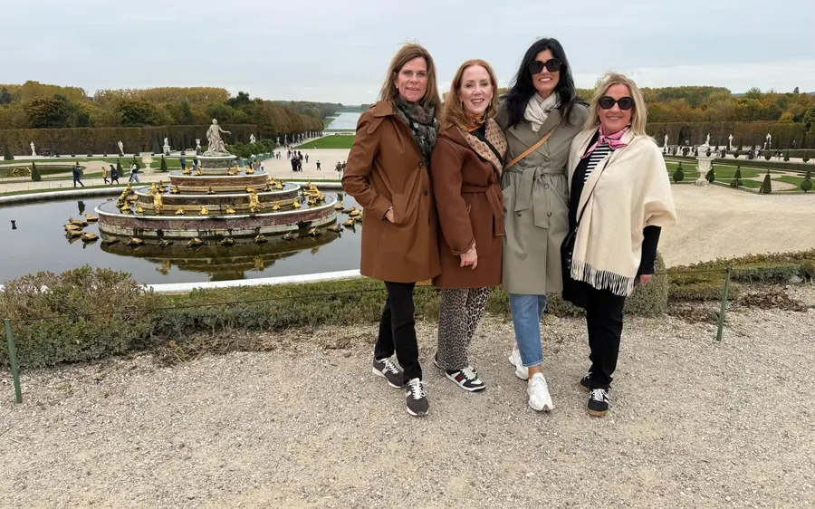 Four women at the edge of a basin in the gardens of Versailles